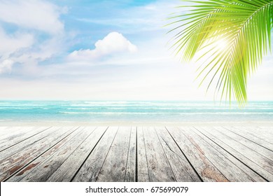 Empty wooden table and palm leaves with party on beach blurred background in summer time. - Shutterstock ID 675699079