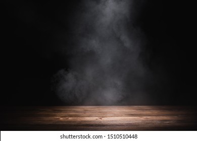 empty wooden table with smoke float up on dark background