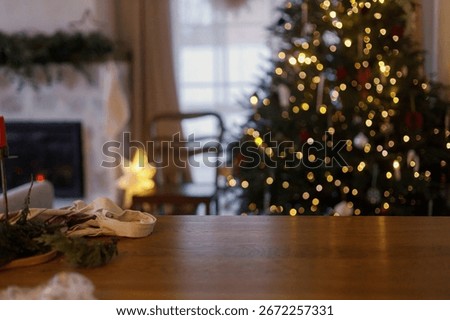 Empty wooden table surface on background of decorated christmas tree with lights and fireplace in nordic living room in magical eve. Wooden desk template , holiday advertising. Merry Christmas!