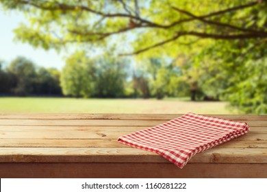 Empty wooden table with tablecloth over autumn nature park background 