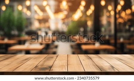 The empty wooden table top with blur background of restaurant. Exuberant image.
