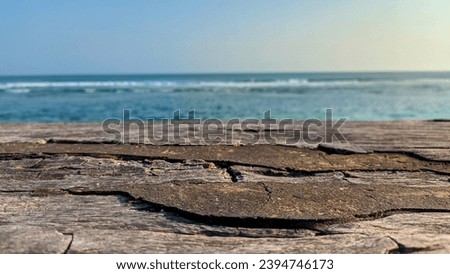 Empty wooden table top with hazy sea and blue sky background. Beautiful and spacious sea summer scene with blank Space for text. Blank ready for your product display montage.