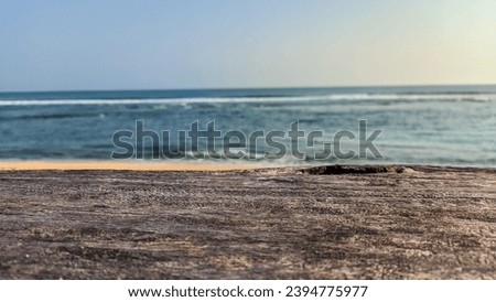 Empty wooden table top with hazy sea and blue sky background. Beautiful and spacious sea summer scene with blank Space for text. Blank ready for your product display montage.