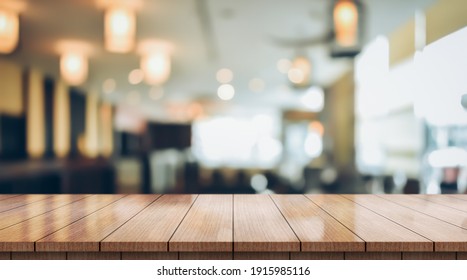 Empty wooden table top with lights bokeh on blur restaurant background. - Shutterstock ID 1915985116