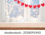 Empty wooden table top on blurred window interior decorated with red heart garland of valentine day celebration