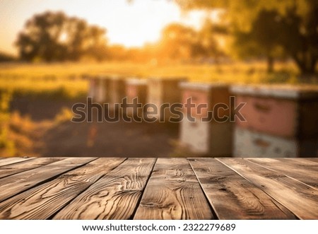 Empty wooden table top for product display. In the background, a blurred background of a small apiary at sunset.
