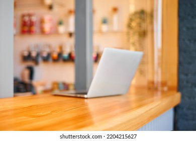 Empty Wooden Tabletop And Blurry Laptop. Product Display Template With Copy Space. Cafe Interior Mockup