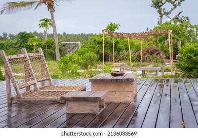 Empty Wooden Terrace With Lounge Beds And Table. Wooden Patio After Rain. Wet Terrace In Tropical Resort. Backyard In Summer Tourist Resort. Outdoor Furniture.