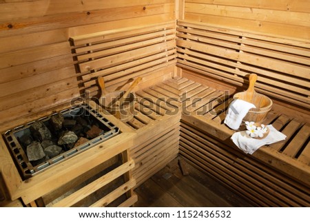 Empty wooden traditional sauna room.Hot stone, wooden bucket with accessories in the spa room.Selective focus.