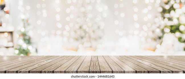 Empty woooden table top with abstract warm living room decor with christmas tree string light blur background with snow,Holiday backdrop,Mock up banner for display of advertise product