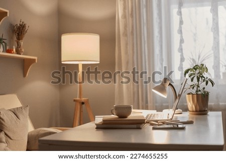 Empty workplace of modern freelancer, open laptop computer, flower in pot, smart phone, copybook on desk in stylish home office interior