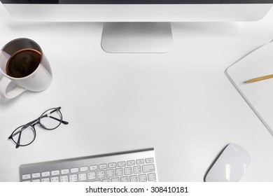 Empty Workspace On White Table. View From Above On The Clean, Well Organized Working Space Framed By PC, Keyboard, Mouse, Pencil, Coffee Cup And Glasses