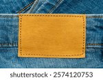 Empty worn leather patch on blue jeans. Empty space for writing. Blank leather jeans label