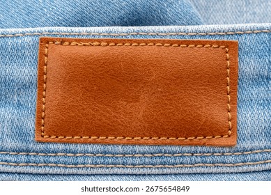 Empty worn leather patch on blue jeans. Empty space for writing. Blank leather jeans label