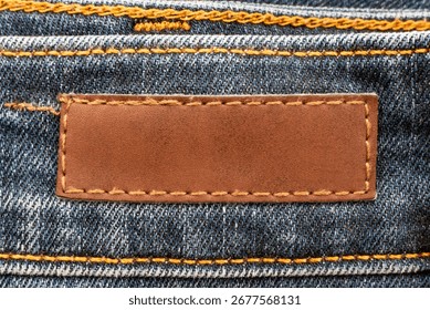 Empty worn leather patch on blue jeans. Empty space for writing. Blank leather jeans label