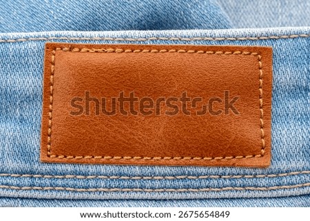 Empty worn leather patch on blue jeans. Empty space for writing. Blank leather jeans label