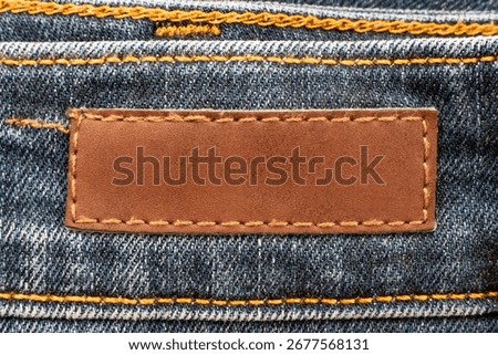 Empty worn leather patch on blue jeans. Empty space for writing. Blank leather jeans label