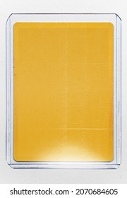 Empty Yellow Trading Card With No Content Or Picture Behind Transparent Plastic Top Loader Case On White Paper Background. Trading Card Mock Up.