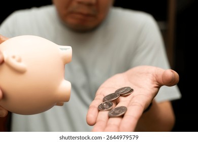 Emptying Piggy Bank, Man Counting Coins. a small pile of coins in the palm of his hand, indicating a limited amount of savings. insufficient savings, financial struggles. - Powered by Shutterstock - Get 15% off with code: PIKWIZARD15