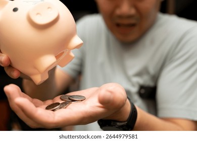 Emptying Piggy Bank, Man Counting Coins. a small pile of coins in the palm of his hand, indicating a limited amount of savings. insufficient savings, financial struggles. - Powered by Shutterstock - Get 15% off with code: PIKWIZARD15