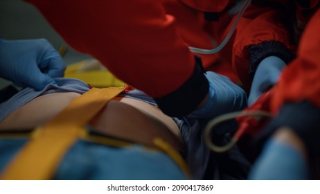 EMS paramedics rescuing patient in oxygen mask. Ambulance crew preparing medical equipment for fist aid help. Medical assistants resuscitating man in ambulance car during way to hospital - Powered by Shutterstock