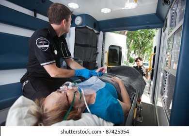 EMT Professional Check Pulse On Elderly Woman In Ambulance