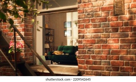 Emtpy And Stylish Loft Apartment With Modern Furtiture And Abstract Art Pieces On The Wall. No People In Cozy And Comfotable Flat With Sun Shining Inside. Shot Throught Apartment Window.