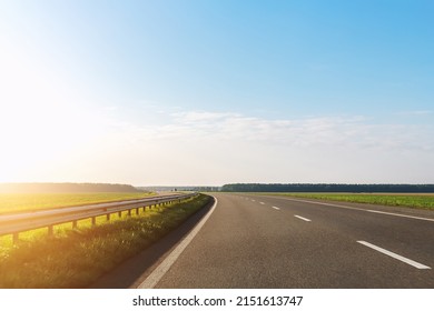 Emtpy view suburaban highway car road with motion blurred fast speed driving against blue sky on background at warm morning sunrise or sunset. Perspective panoramic vehicle motorway landscape