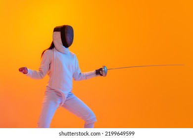 En garde. Studio shot of professional fencer in white fencing costume and mask in action, motion isolated on orange color background. Concept of sport, youth, activity, skills, achievements, ad. - Powered by Shutterstock