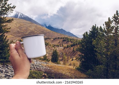 Enamel White Mug Mockup With Forest And Mountains Valley Background. Trekking Merchandise And Camping Geer Marketing Photo. Stock Wildwood Photography With White Metal Cup. 