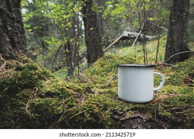 Enamel White Mug In The Mossy Wood Mockup. Trekking Merchandise And Camping Geer Marketing Photo. Stock Wildwood Photo With White Metal Cup. Rustic Scene, Product Mockup Template. Lifestyle Outdoors.