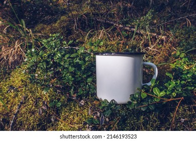 Enamel White Mug In The Mossy Wood Mockup. Trekking Merchandise And Camping Geer Marketing Photo. Stock Wildwood Photo With White Metal Cup. Rustic Scene, Product Mockup Template. Lifestyle Outdoors.