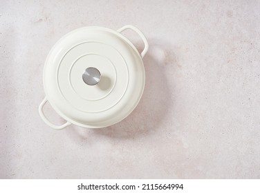 enameled cast iron pot, white cocotte new lidded isolated on pink stoneware background. Top view with copy space.