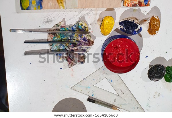 Encaustic painting, also known as\
hot wax painting, colored pigments, heated beeswax, untreated wood.\
Metal tools and special brushes on the table in the\
workshop