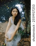 Enchanting Forest Portrait of a Young Woman in a Flowing White Dress Sitting by a Tranquil Stream, Capturing Natural Beauty and Serenity.