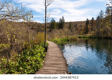 Enchanting hiking trail on rustical wooden footpath in magical Plitvice lakes National Park, Karlovac, Croatia, Europe. Walking over calm waters in serene nature. Idyllic autumn landscape. Wanderlust - Powered by Shutterstock