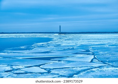 An enchanting winter scene with a tranquil reservoir, vibrant blue ice, and a solitary lighthouse.