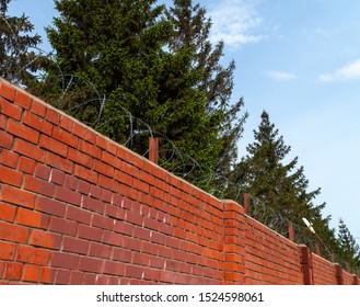 Enclosed area behind a brick wall with barbed wire. Protection from migrants and escapes. - Shutterstock ID 1524598061