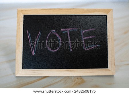 Encourage voter turnout and political activism with this impactful stock photo featuring a chalkboard bearing the simple yet powerful message: VOTE.