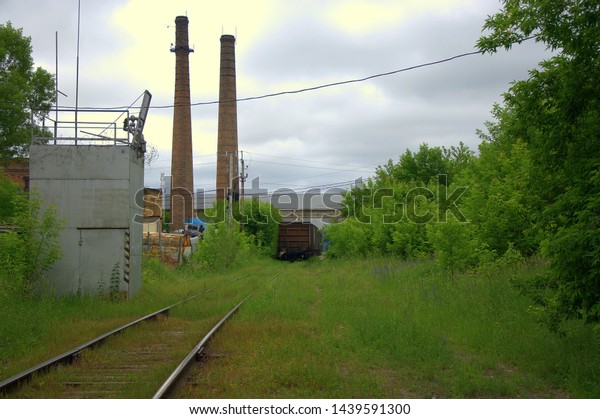 The end of an abandoned railway line\
of old cars and pipes of an abandoned\
factory.