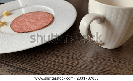At the end of a hotel breakfast.Table view. Slice of salami and coffeecup.