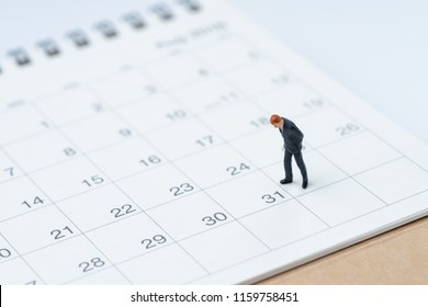 End of month for salary man concept, miniature people businessman office guy standing and looking at number 31 date, waiting to get money and pay day.