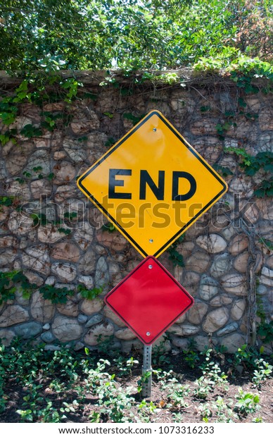 End road sign against stone\
wall