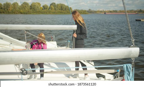 End Of The Sailing Season. On A Cold Autumn Day, Female Sailing Athletes Dismantle The Rigging Of The Yacht For Winter In The Dock.