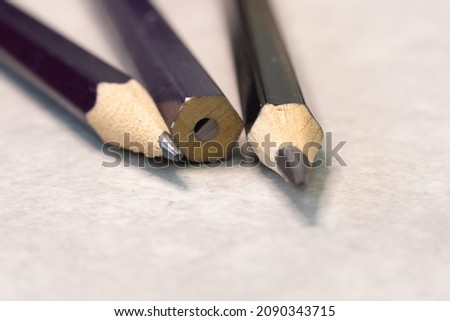 An end view of a group of three  graphite pencils with the central one with a plain end unsharpened.
