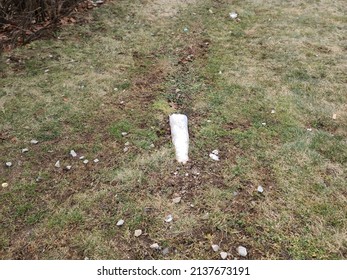 The end of a white plastic drain pipe coming out a grassy hill.