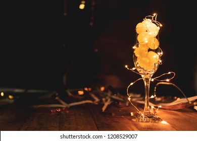 End Of The Year Concept. Glass Of Champagne With Grapes Inside, With Holiday Decoration