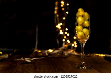 End Of The Year Concept. Glass Of Champagne With Grapes Inside, With Holiday Decoration