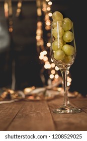 End Of The Year Concept. Glass Of Champagne With Grapes Inside, With Holiday Decoration