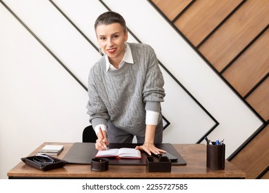 endearing female accountant with a cute smile at her desk looking at the camera
